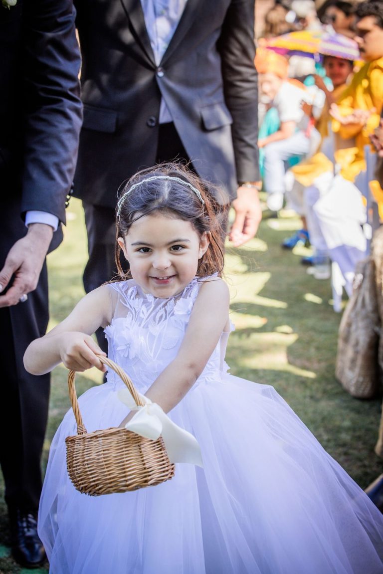 Smiling flower girl reaching into petal basket during processional