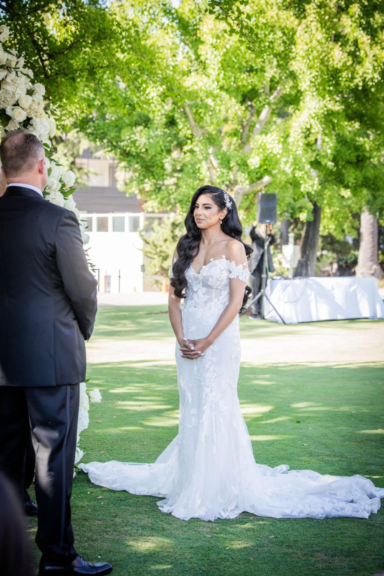 Bride and groom facing each other on green lawn