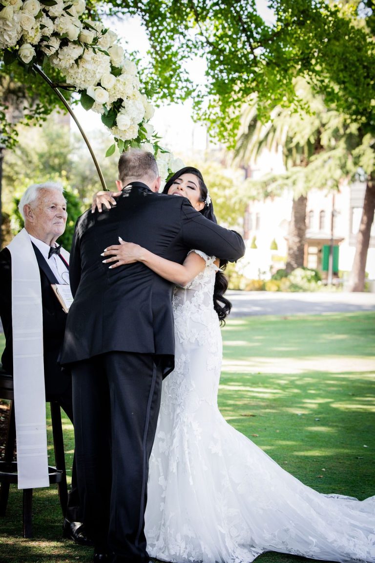 Bride embracing groom warmly on green lawn