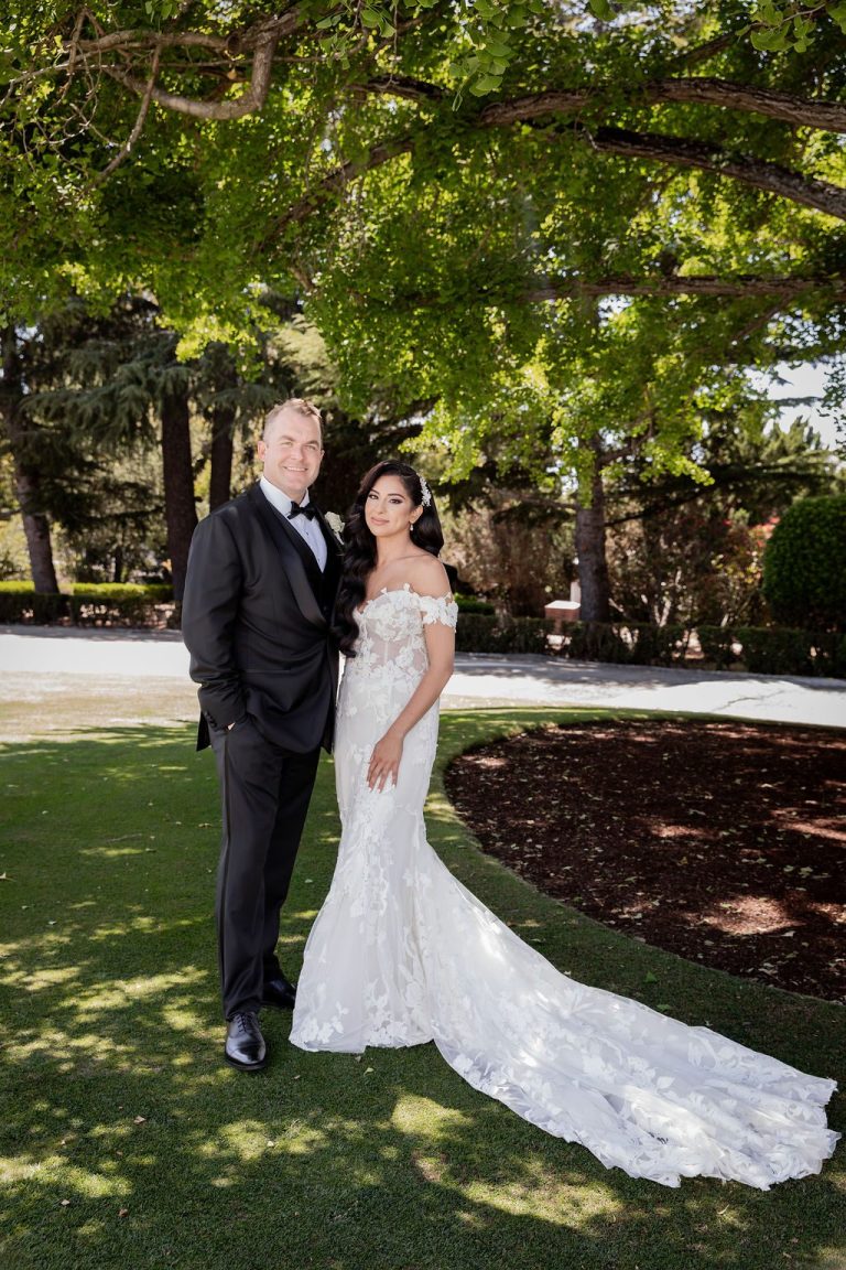 Bride and groom standing together on manicured lawn
