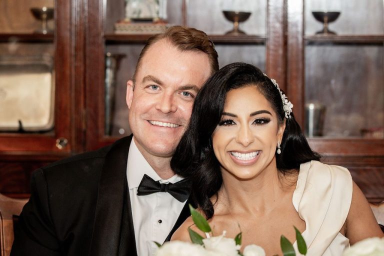 Bride and groom smiling closely at reception head table