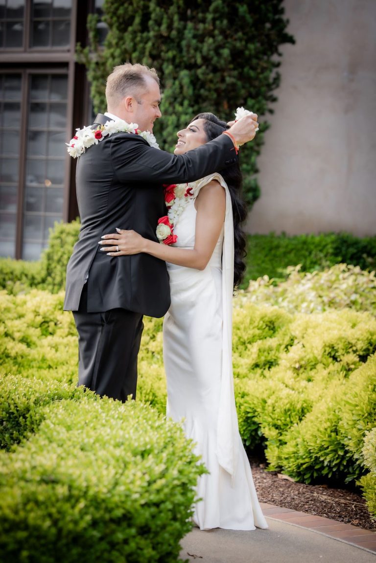 Groom lifts bride in garden with floral leis