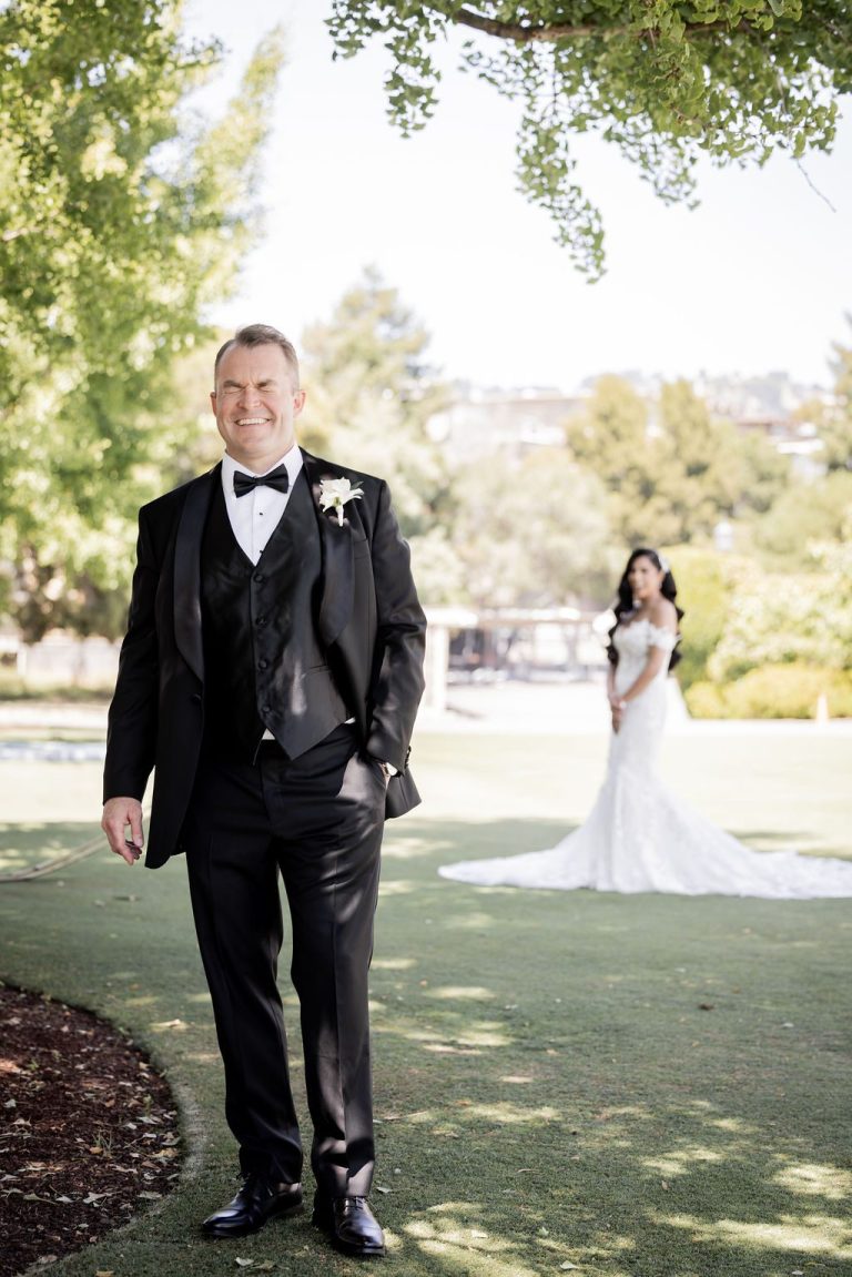 Groom looking to side with bride waiting behind