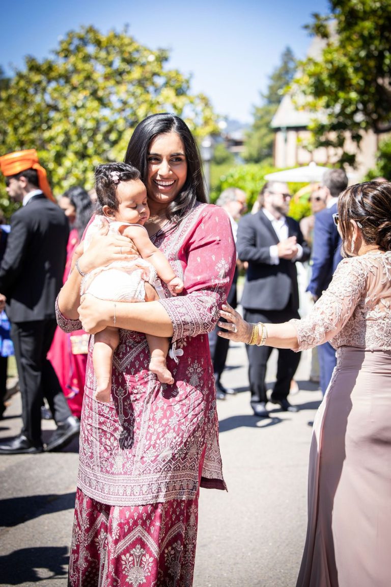 Woman in pink holding small child among guests
