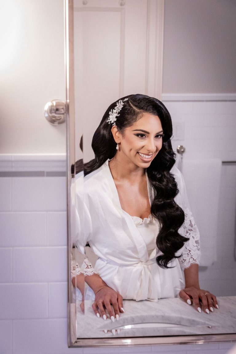 Bride smiling into mirror, hair styled in waves