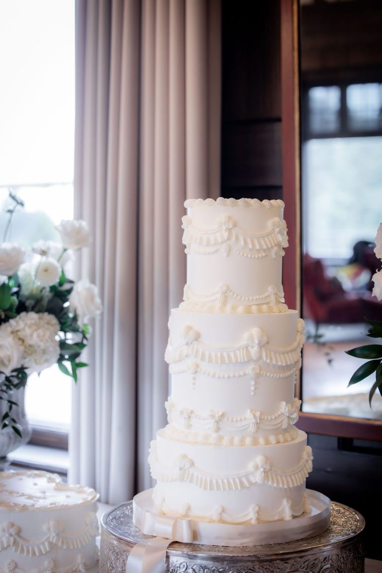 Tall white tiered cake near draped window