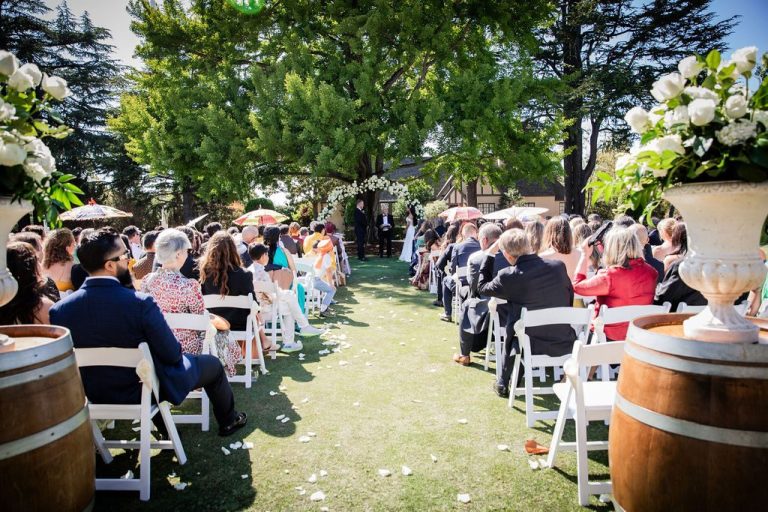 Aisle view of ceremony with seated guests and arch