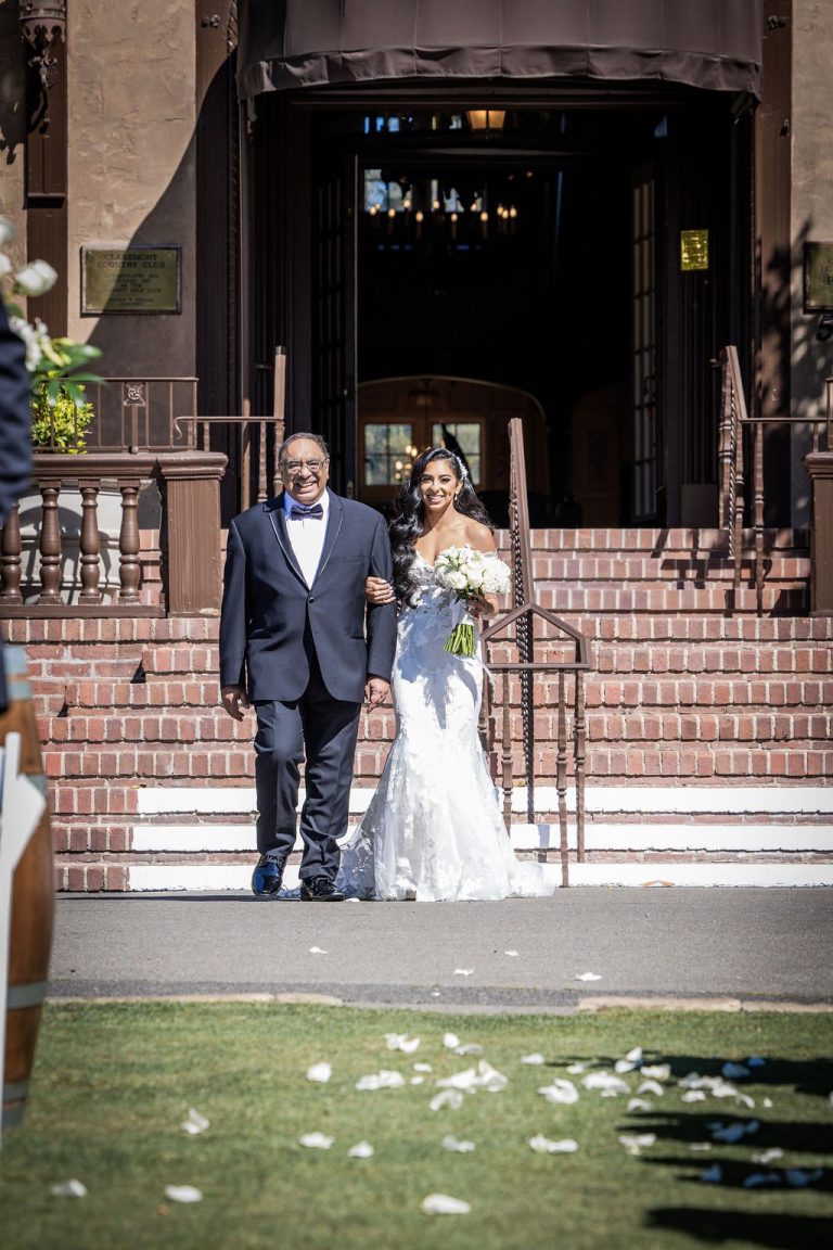 Bride and escort descending steps onto petal-lined lawn