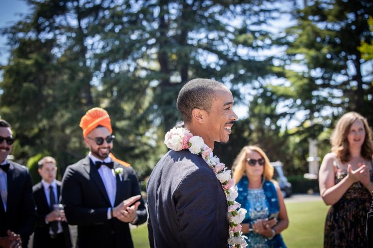 Smiling guest wearing floral garland among wedding party