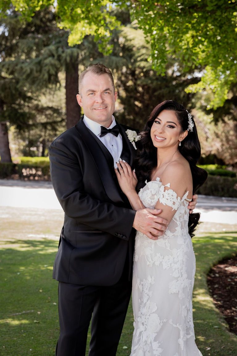 Bride holds groom lapel during tender lawn portrait