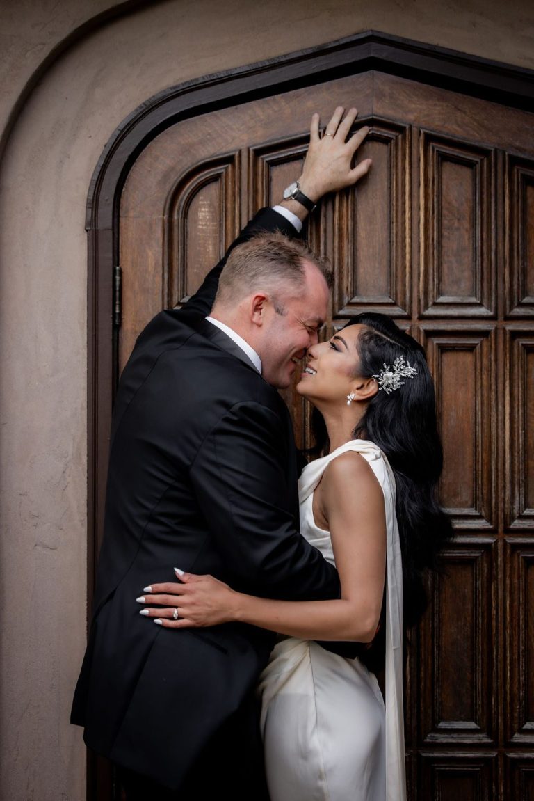 Passionate dip kiss before ornate arched wooden door