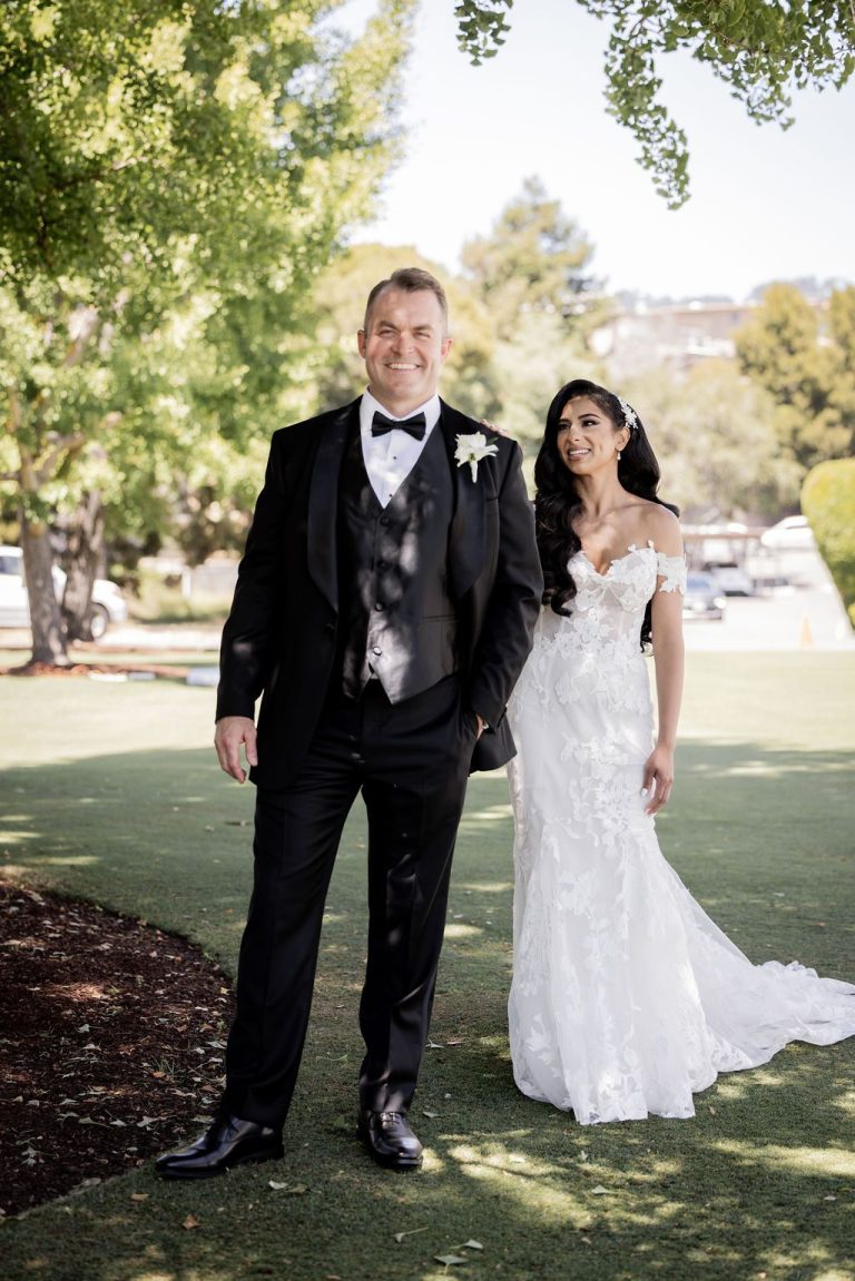 Groom and bride smiling side by side on lawn