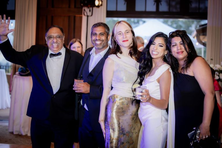 Bride poses with family group smiling at camera