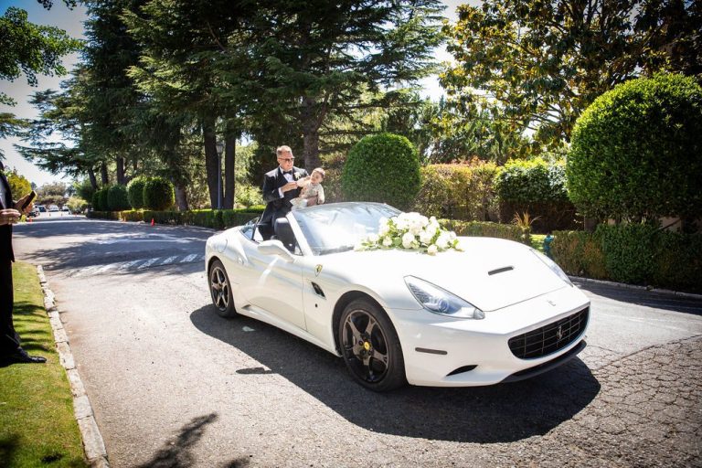 Groom stands cheering in decorated white sports car