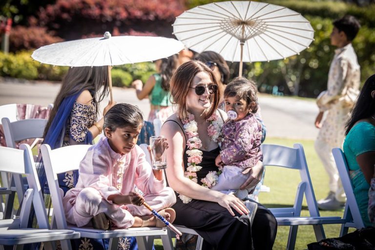 Guests seated with parasols at outdoor ceremony