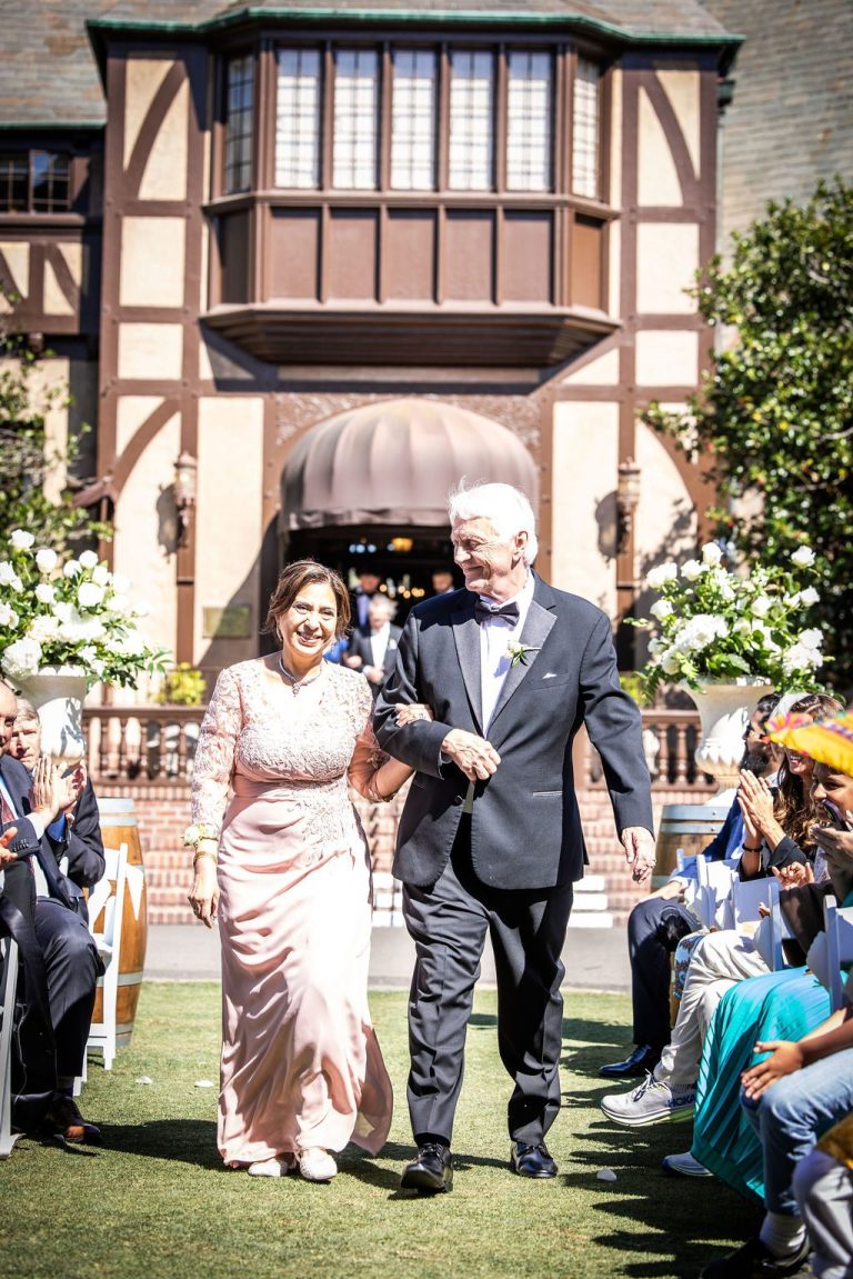 Couple walking ceremony aisle past guests outdoors