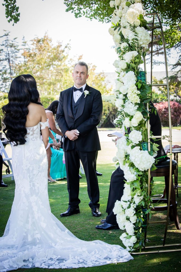 Bride from behind facing groom under floral arch