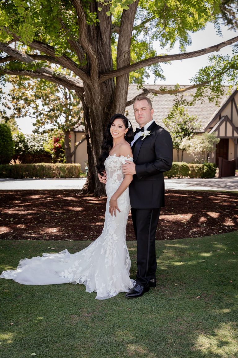 Couple embrace under sprawling tree with dappled light