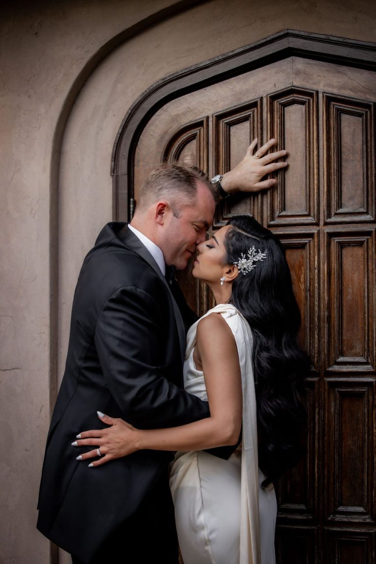 Couple kissing, groom leaning against wooden door