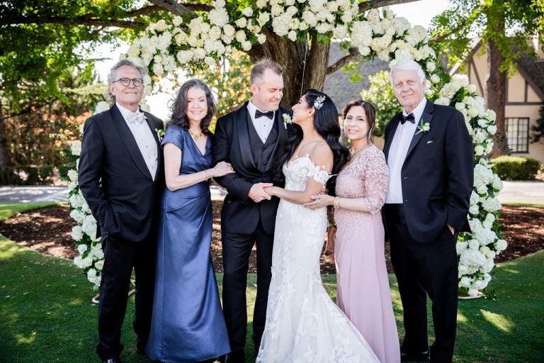 Couple laughing with parents during arch group portrait