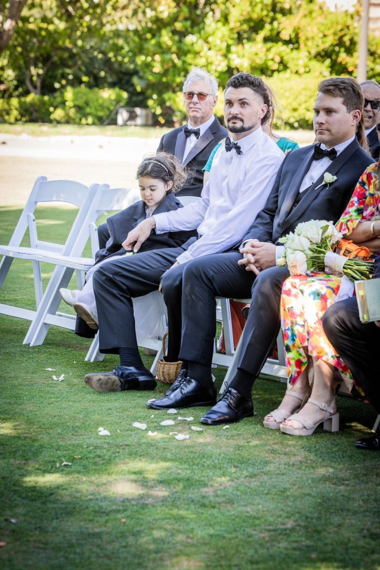 Young guest holding bouquet seated among family