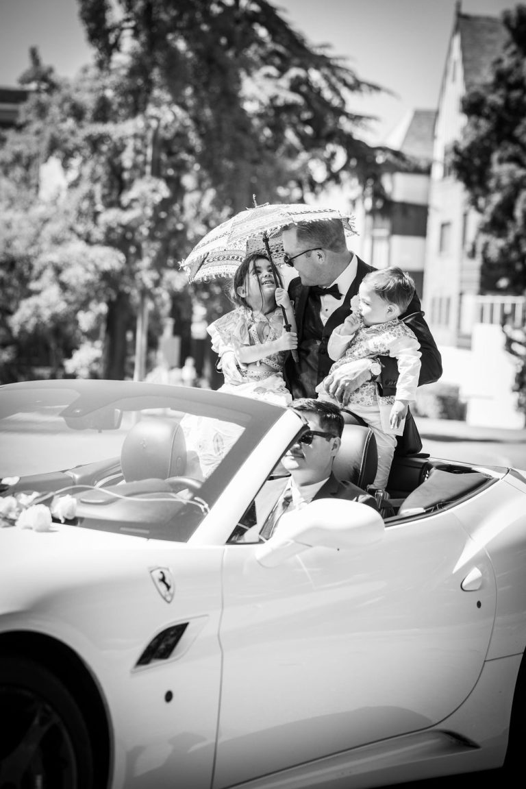 Black and white man holding child in decorated sports car