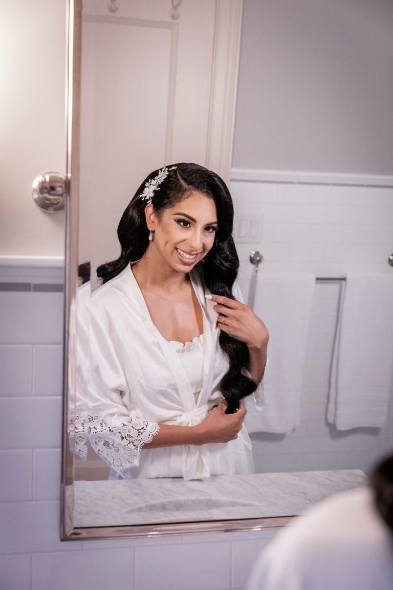 Bride smiling in mirror reflection during prep