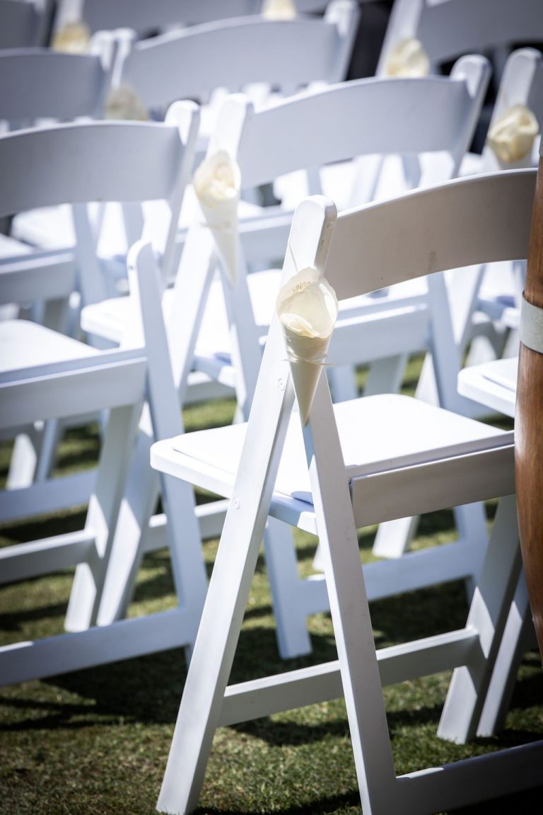 White ceremony chairs with floral ties on lawn