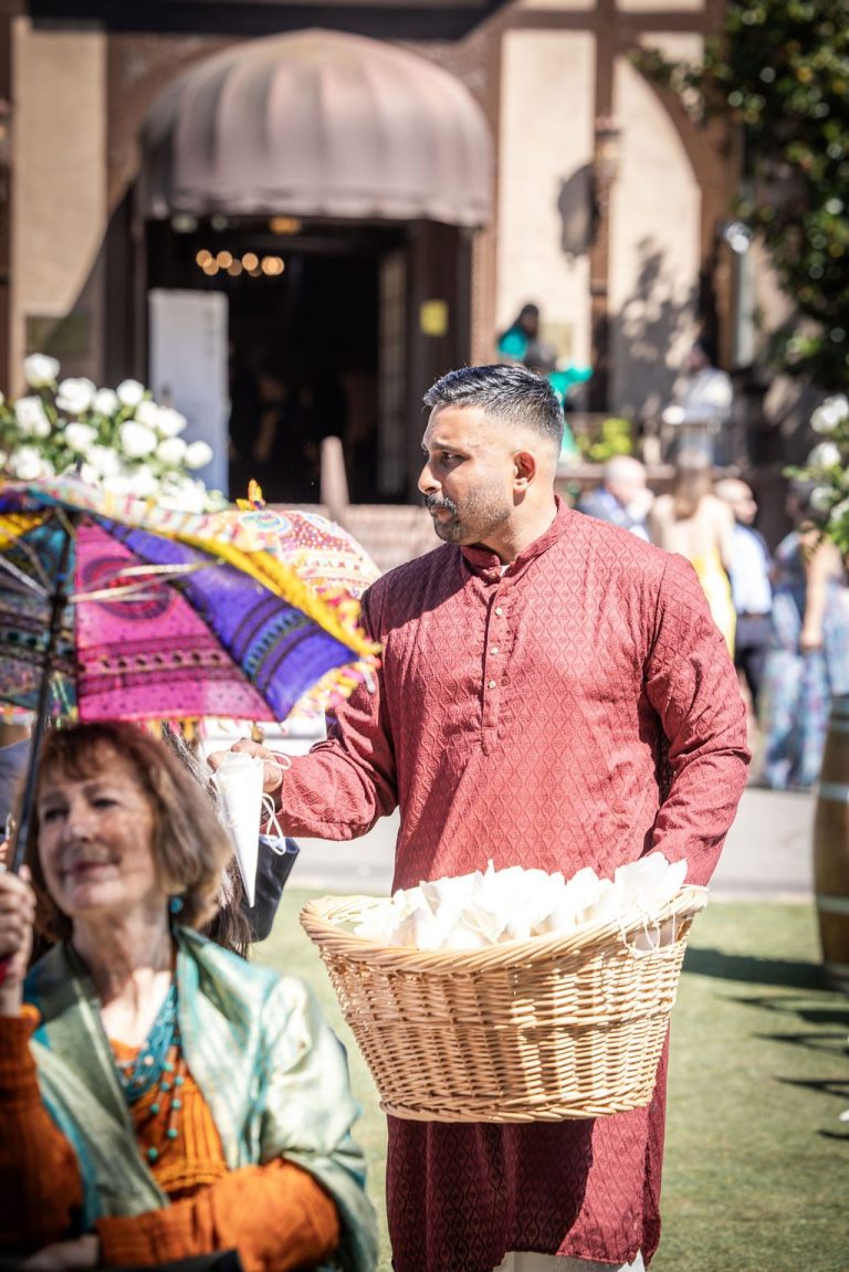 Man carrying petal basket down aisle in kurta