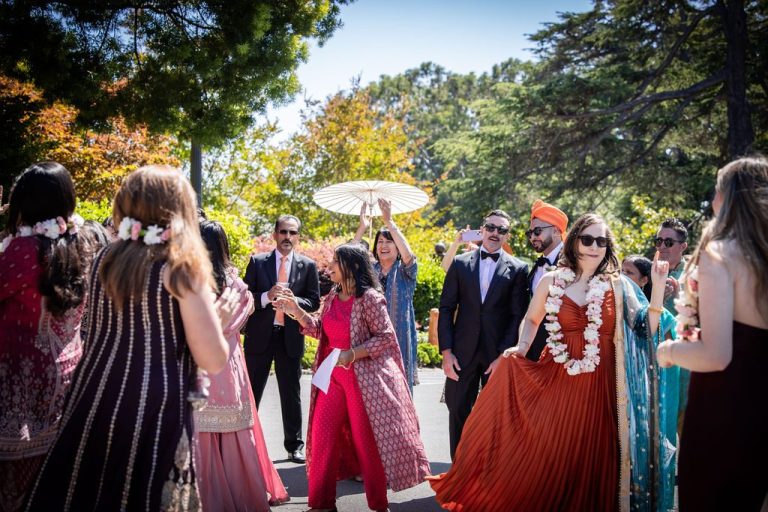 Guests greeting with floral garlands and parasol in sunlight