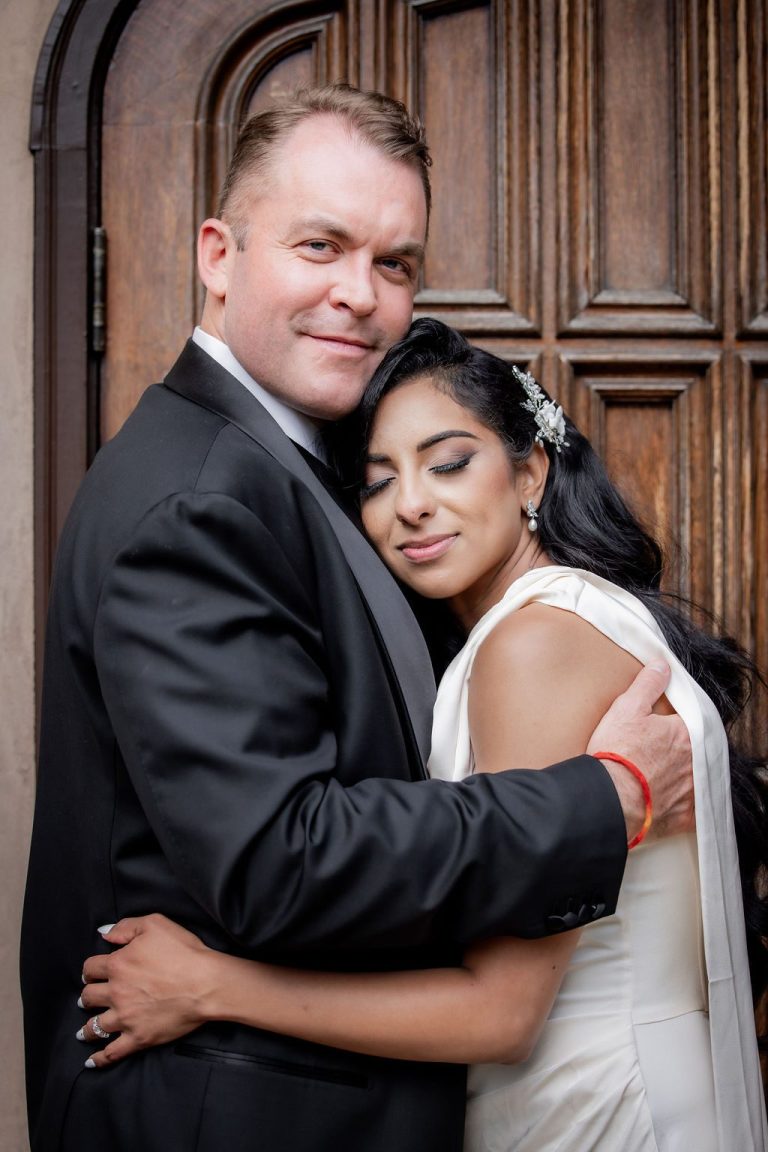 Bride resting head on groom's chest before door