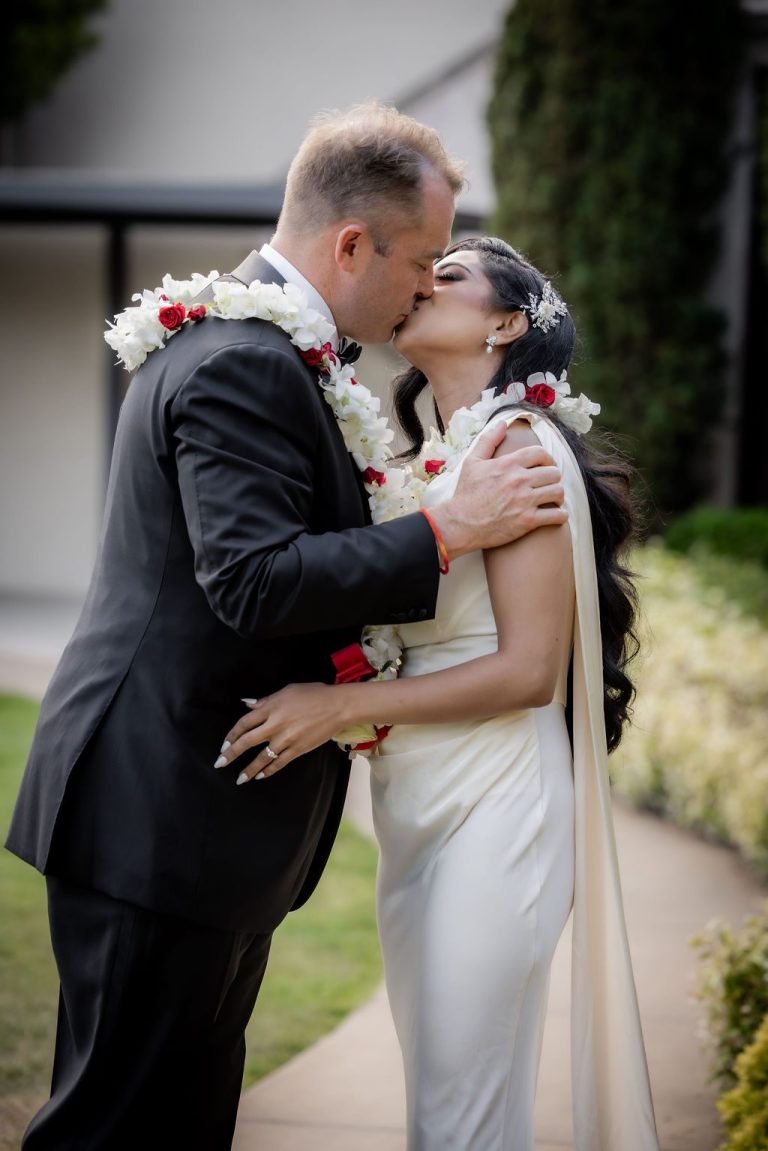 Groom kisses bride tenderly with floral leis