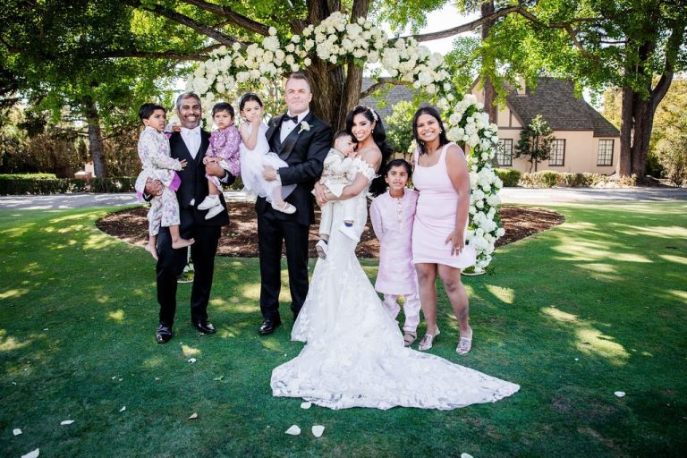 Large family group with children at floral arch