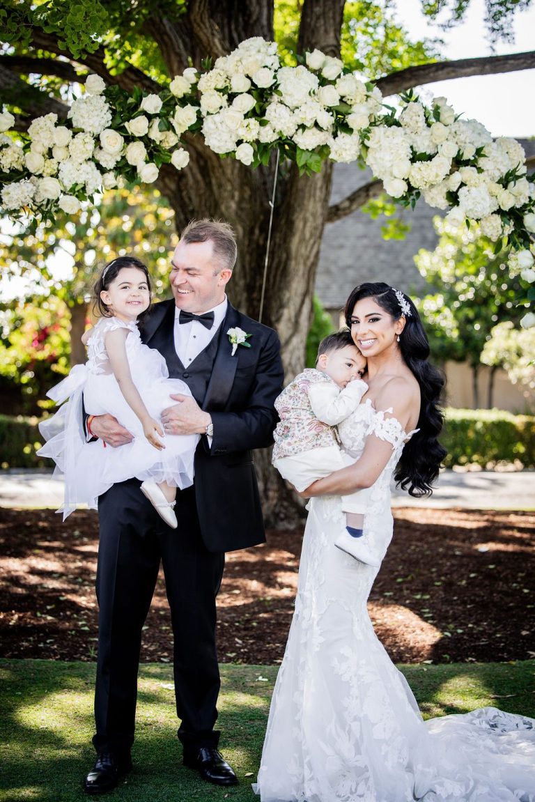 Couple holding two small children under floral arch