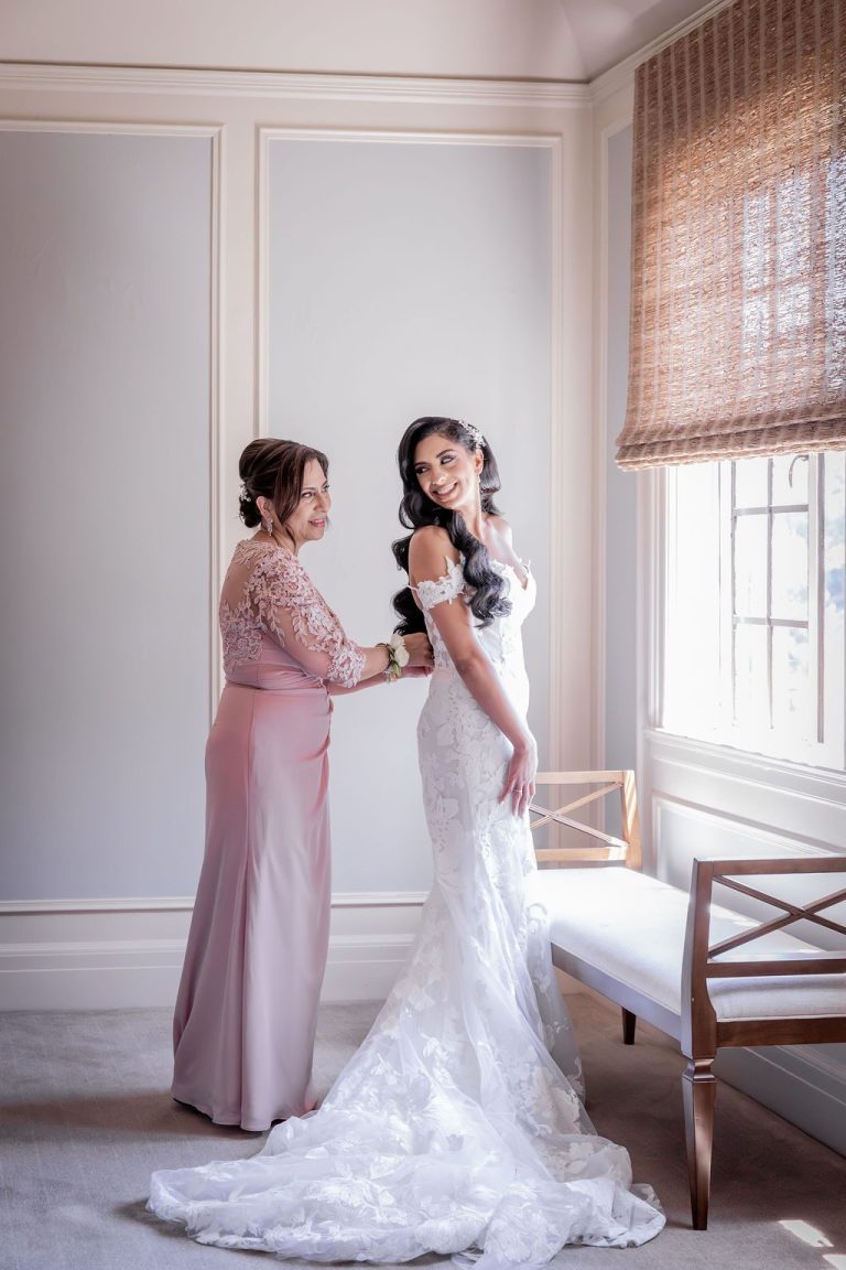 Bride and mother smiling together by bright window