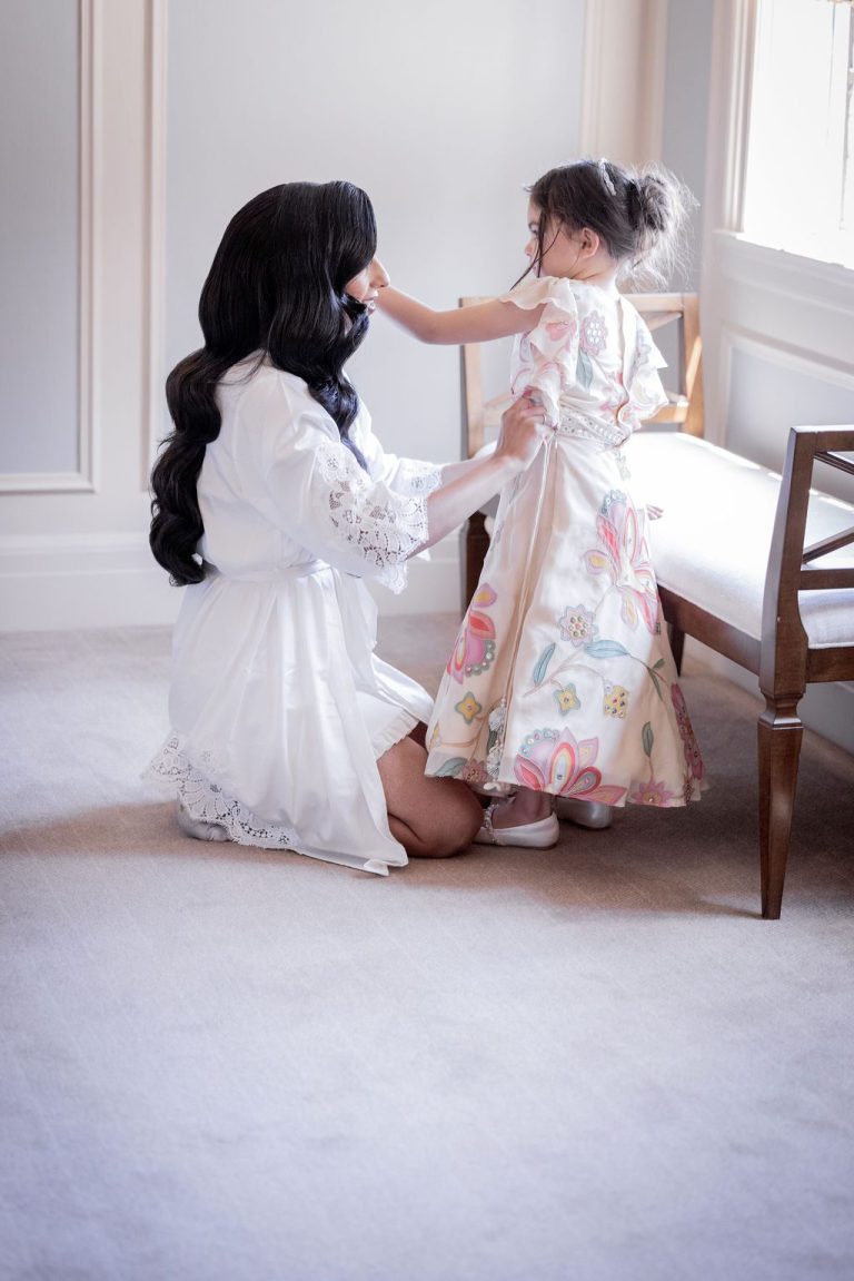 Bride and girl by window from behind getting ready