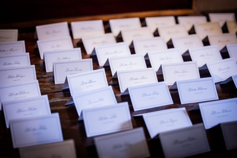 Angled rows of white place cards on wood
