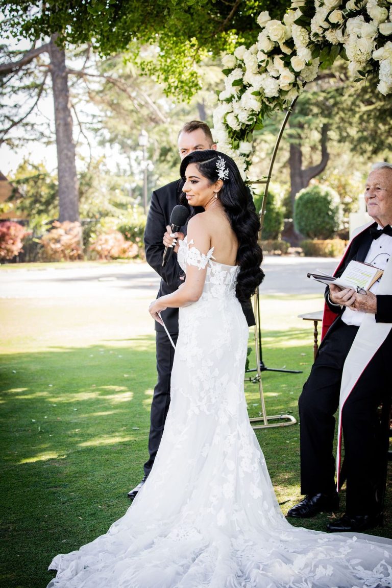 Bride with long train facing groom beside officiant