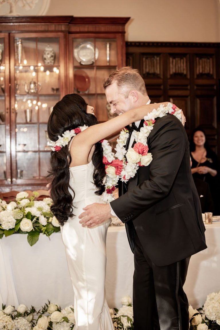 Couple embracing closely, groom wearing floral garland