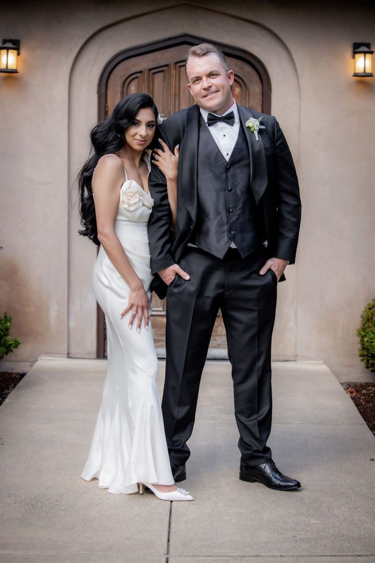 Bride and groom posing elegantly before arched doorway