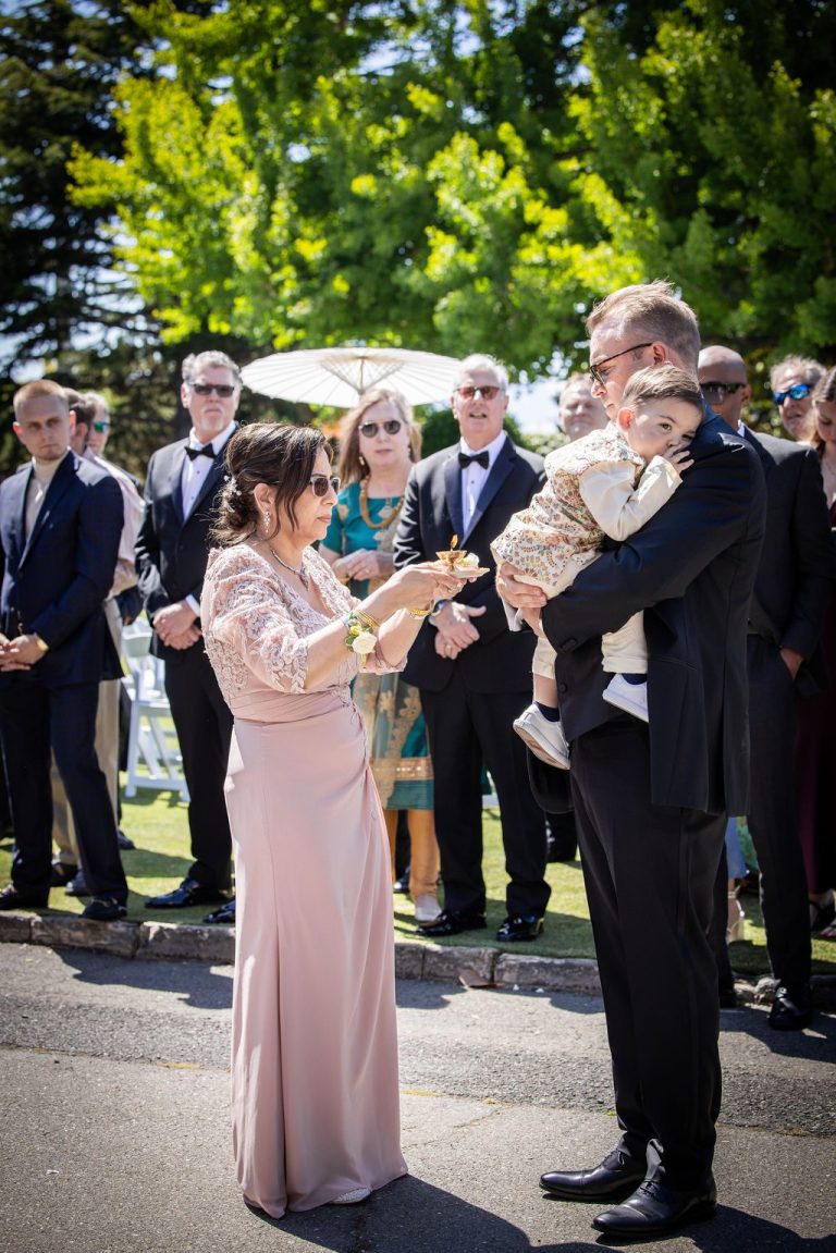 Woman in blush gown embracing man during garland greeting