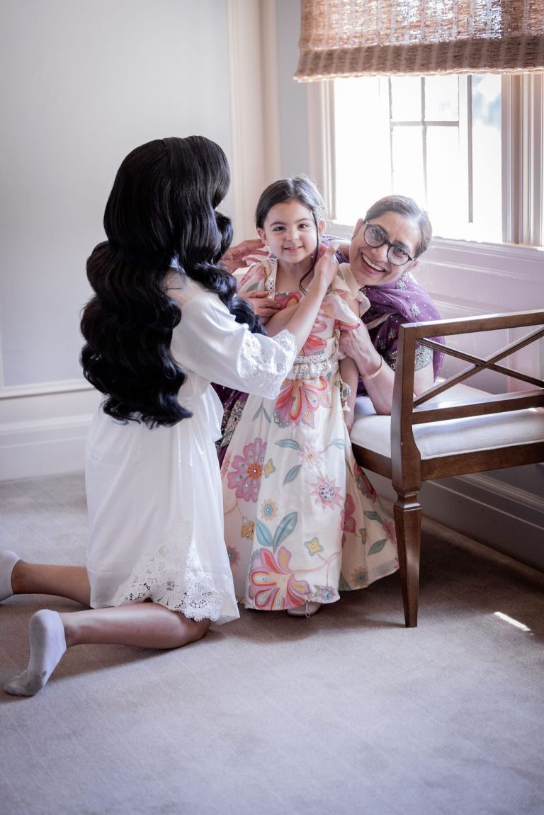 Bride helping girl while older woman looks on