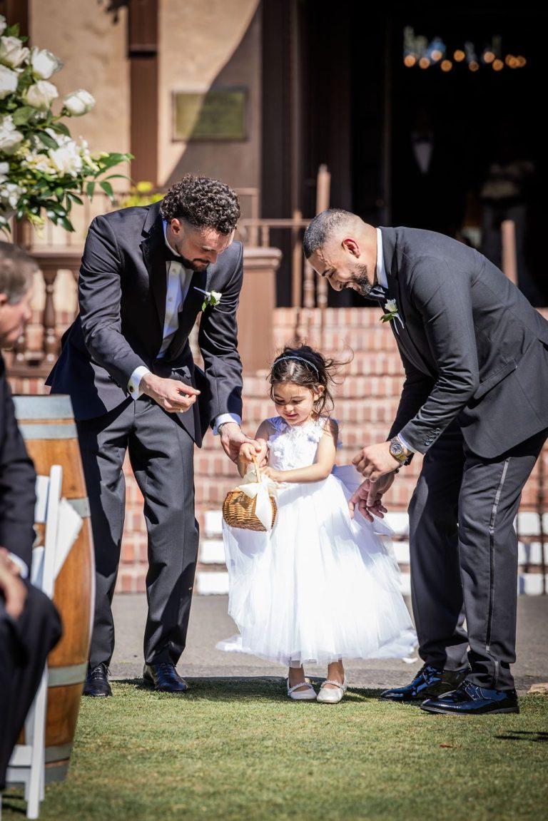 Groomsmen helping flower girl scatter petals down aisle