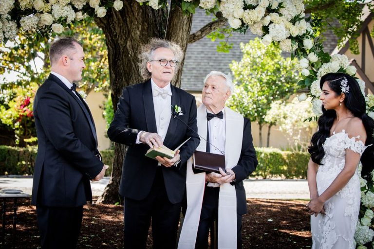 Officiant reading from book beside groom and bride