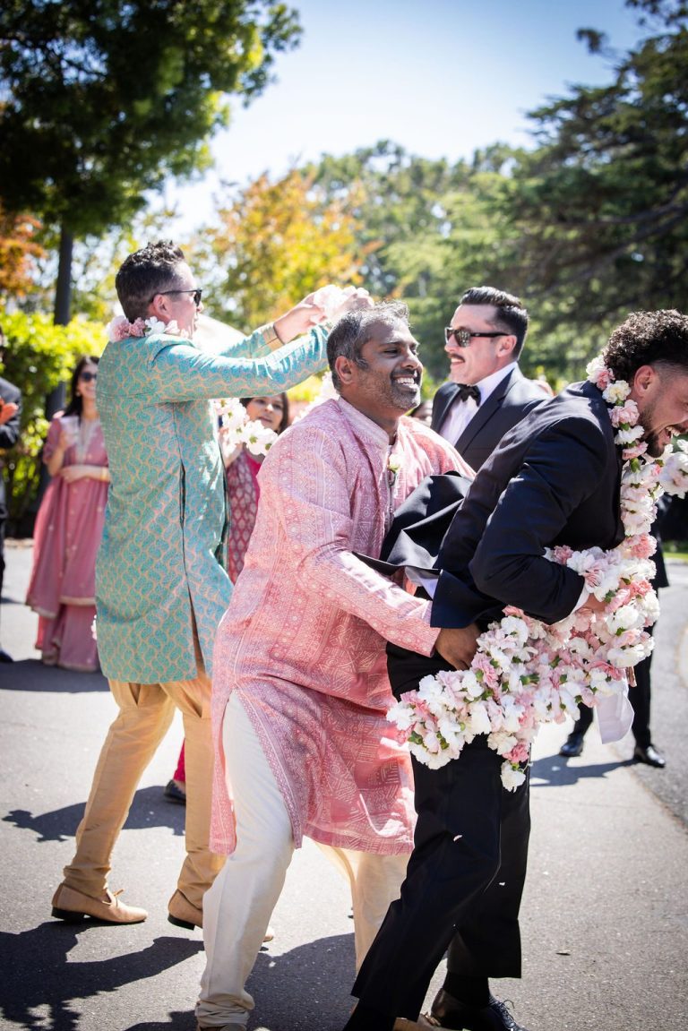 Men embracing warmly with floral garland during procession