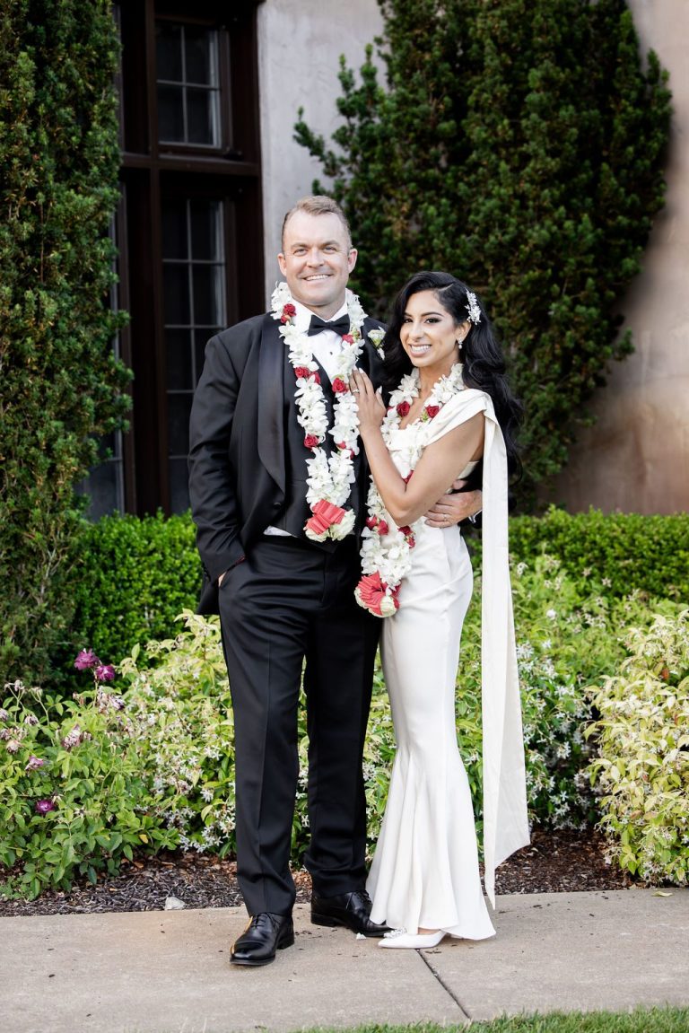 Bride and groom posing in garden with hedges