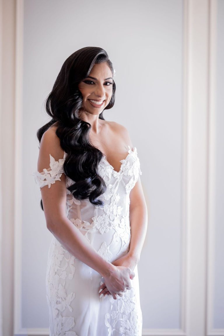 Bride smiling softly with long curled hair in gown
