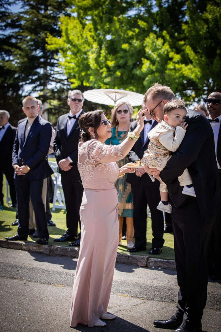 Woman in blush gown greeting man with child outdoors