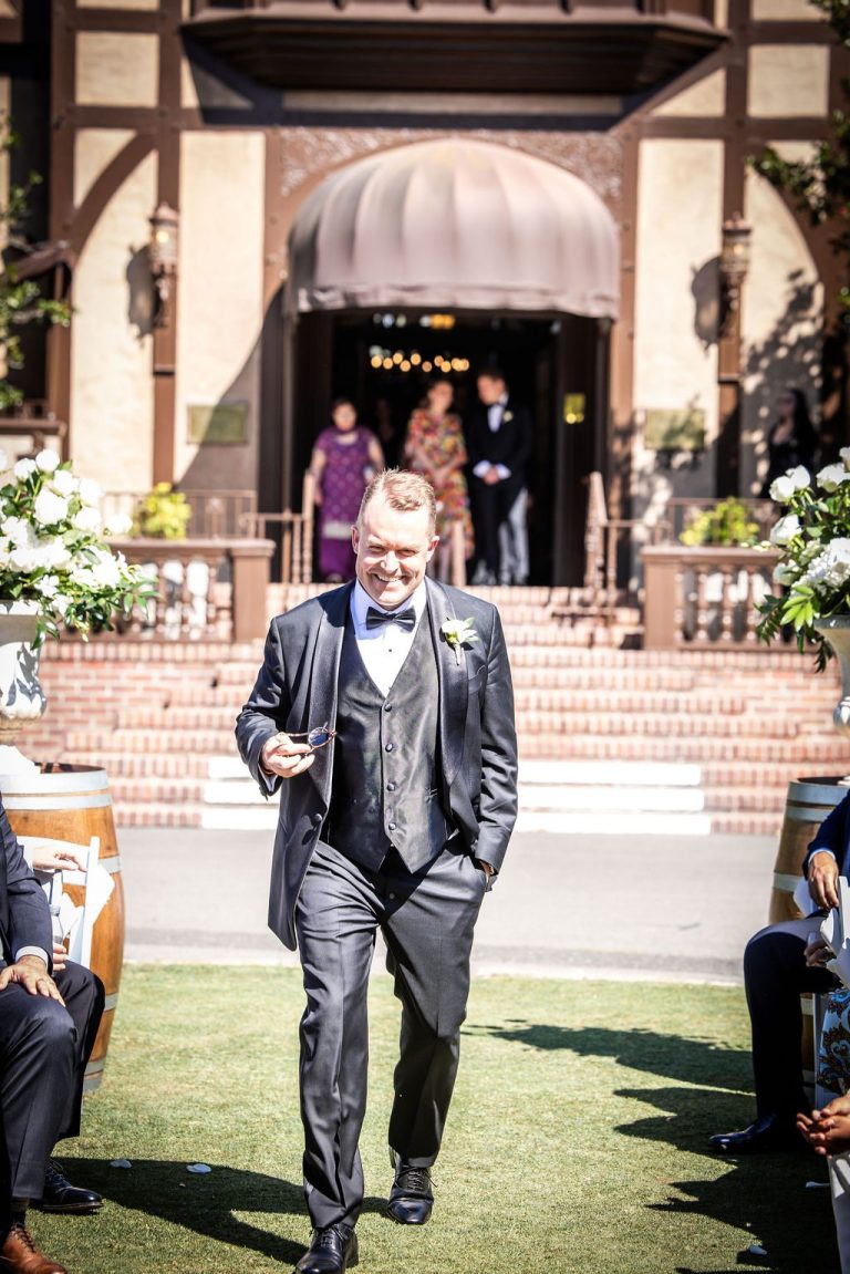 Man in gray suit walking ceremony aisle outdoors