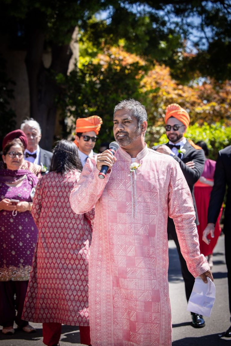 Man in pink outfit singing into microphone during procession